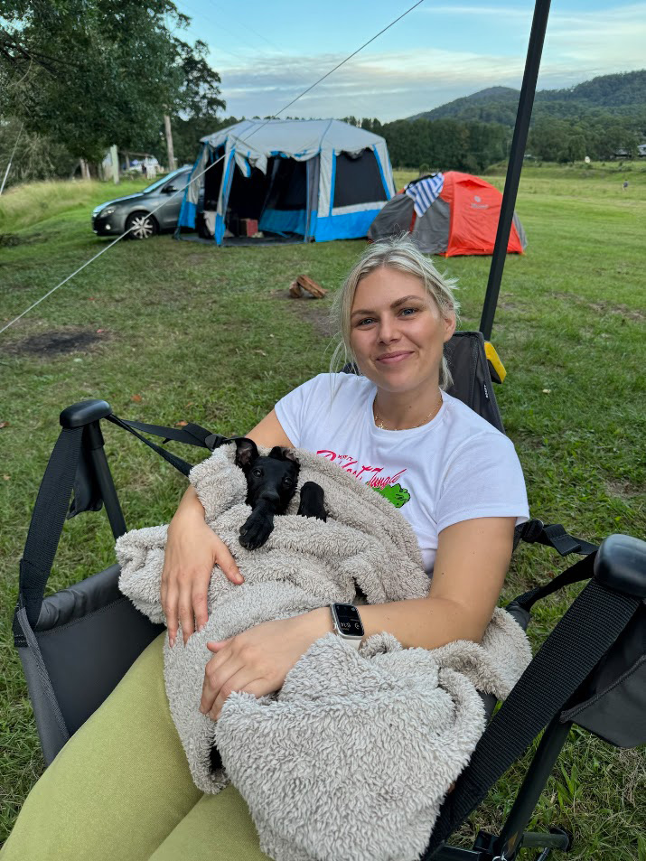 Abby sitting in a camp chair with her puppy whippet, Dov