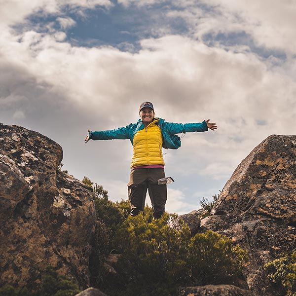 Carolyn standing on a mountain lookout with arms wide