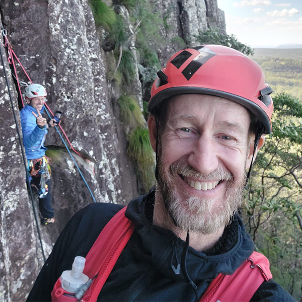 Christian climbing on a wall smiling towards the camera