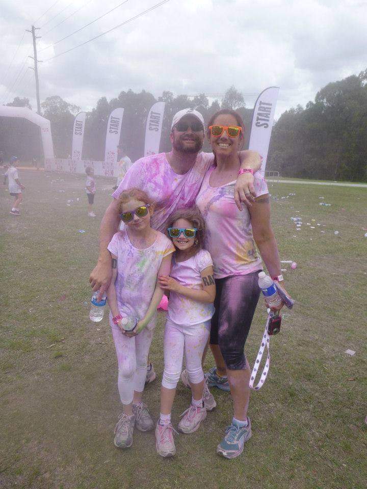 Dani with her husband and 2 daughters at the end of a colour run covered in pink 