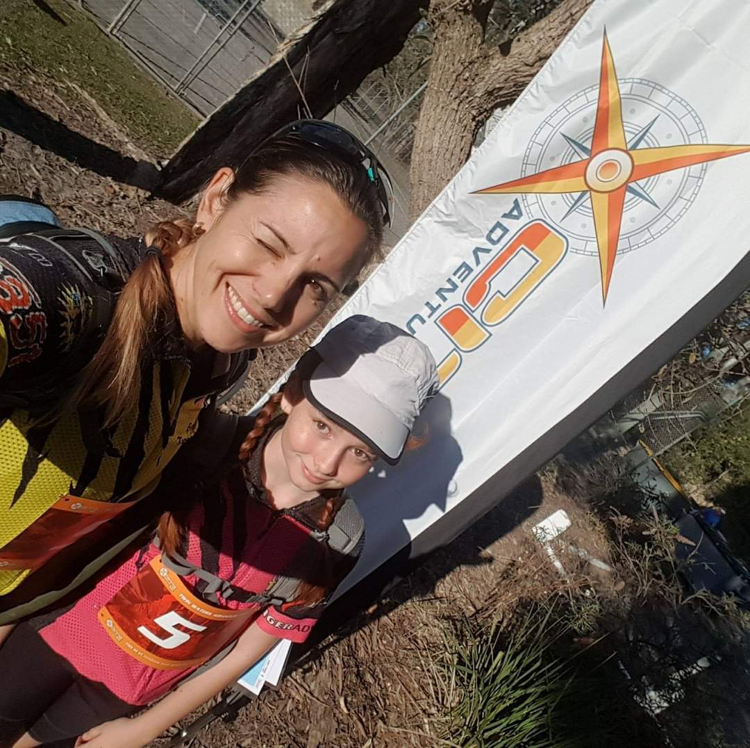 Dani in front of a Adventure Race flag with her daughter