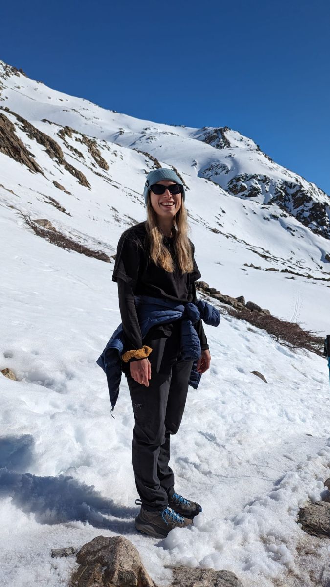 Jess standing on a snowy trail hiking up a mountain in the Arcteryx Konseal Pants