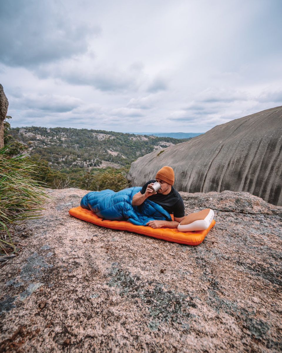 Paul laying on his Big Agnes sleeping pad drinking out of a camp cup