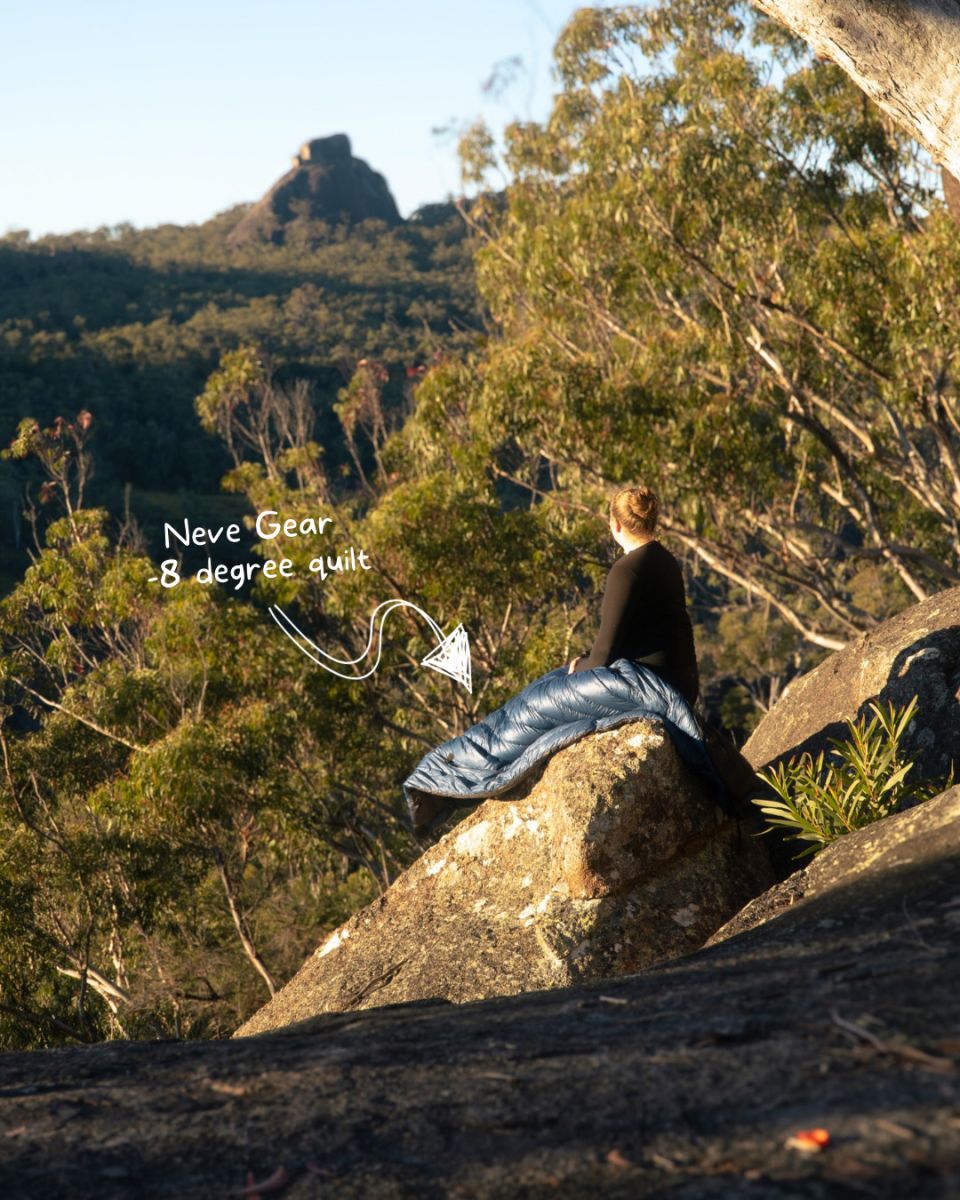 Issy sitting on a rock with the blue Neve quilt with an Australian bush background