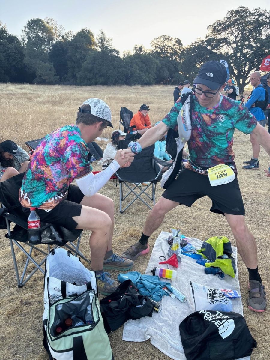 Ryan sitting at a rest station with crew helper, Brody, pulling him up