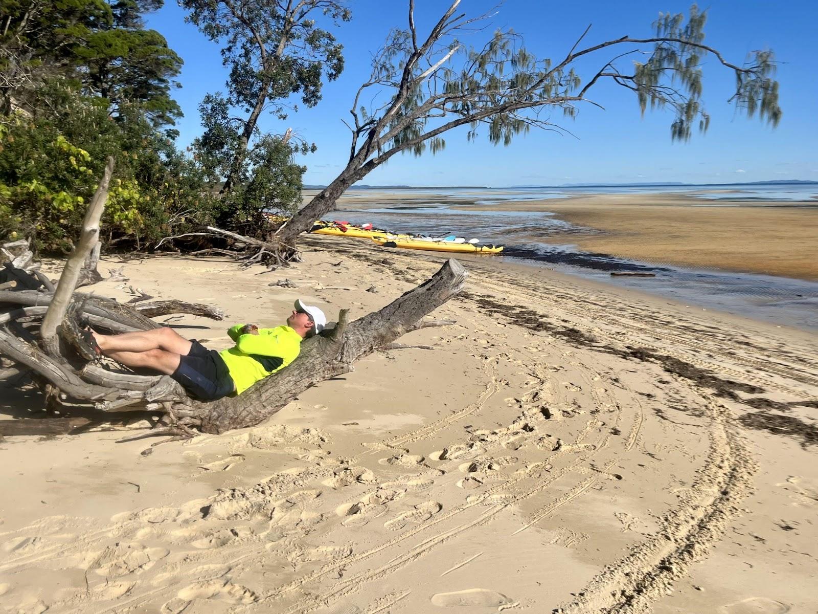 Man sleeping on a log on the beach in the sun